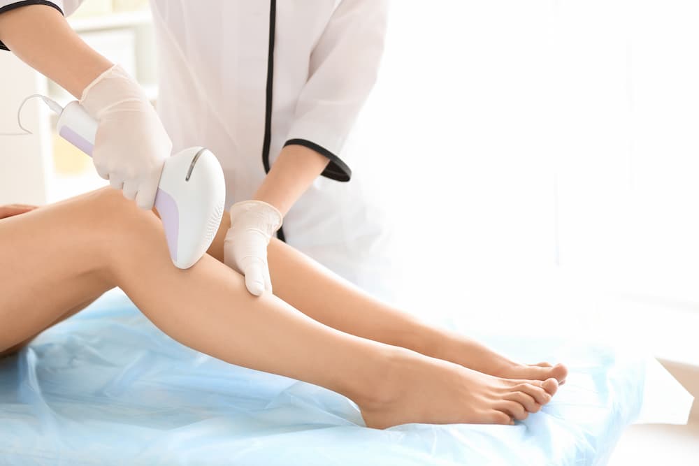 une therapeute qui realise une epilation laser sur les jambes d'une femme