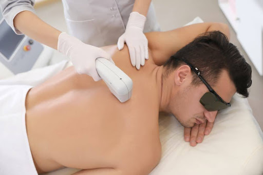 une therapeute qui realise une epilation laser du dos sur un homme